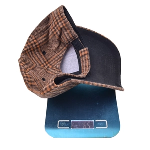 Detailed top view of plaid baseball cap weighing 63 grams on a digital scale