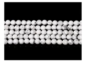 Macro shot of white howlite round beads with grey marble veins on black background