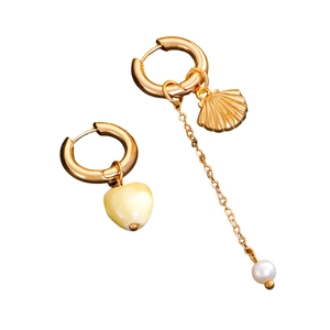 Detail of asymmetric gold earrings with shell charm, pearl chain, and heart pendant