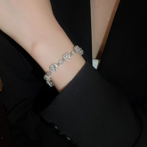 Detailed view of silver heart-shaped zircon bracelet on a model with elegant black suit