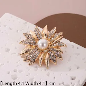 Détail d'une broche fleur dorée de 4,1 cm avec strass et perle centrale blanche