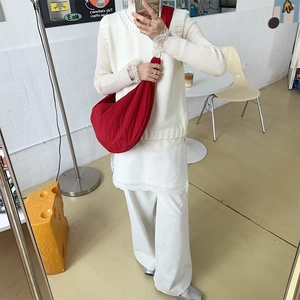 Close-up of red canvas dumpling bag with pleated texture worn on shoulder with white outfit