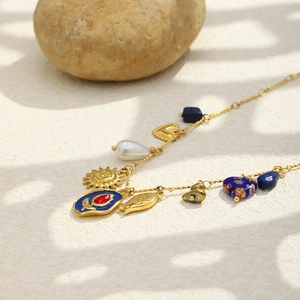 Macro view of 18K gold plated chain with blue enamel sun, pearl, and gemstone charms