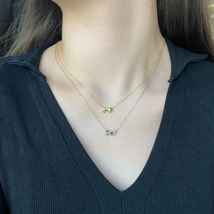 Detail of S925 silver layered necklace with gold and silver heart pendants on model