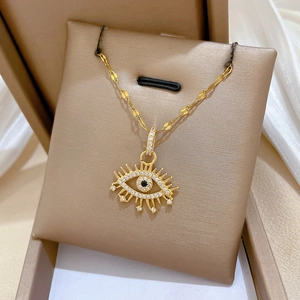 Macro detail of gold eye-shaped pendant with white and black cubic zirconia stones