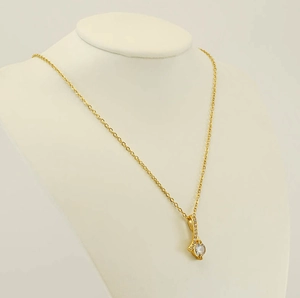 Detail view of a gold-plated teardrop pendant necklace with sparkling zircon on a jewelry stand