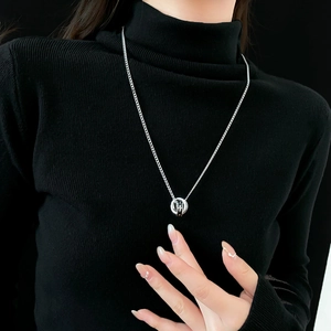 Gros plan du collier à double anneau entrelacé porté par un mannequin sur fond noir