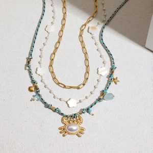 Collana a strati in titanio dorato con corda blu, ciondoli a granchio e stella marina e perle