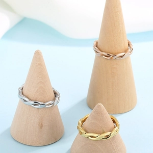 Three-tone twisted rope rings in gold, silver, and rose gold on wooden display stands