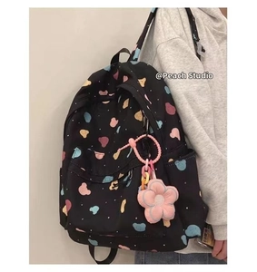 Detail view of cute bear print black canvas backpack with a pink flower plush keychain