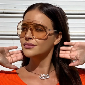 Oversized orange cycling sunglasses and personalized name necklace on a model