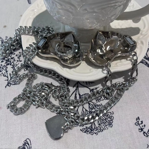 Close-up of heart-shaped silver metal bag charm with magnetic closure and chain