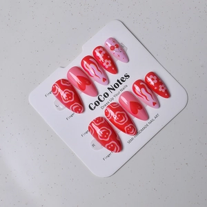 Detailed view of Y2K red heart and cherry almond press-on nails on a display card