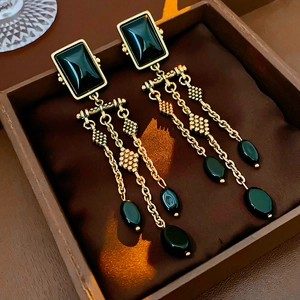 Detail of vintage gold tassel earrings with black stones on a soft jewelry box cushion