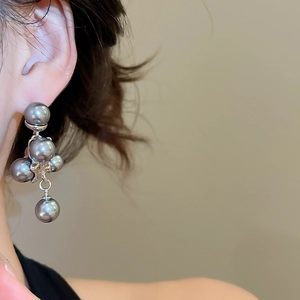 Close-up of a model wearing grey pearl earrings with a vintage metallic design