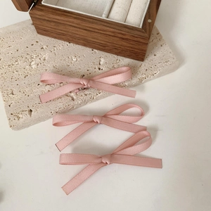 Detailopname van drie roze satijnen haarstrikjes op een minimalistische stenen basis