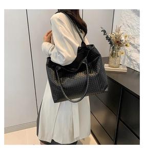 Lifestyle shot of large black woven leather tote bag shown on a model's shoulder
