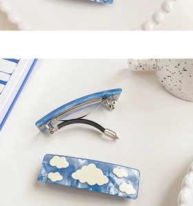 Close-up of blue acetic acid hair claws with white cloud prints and spring mechanism