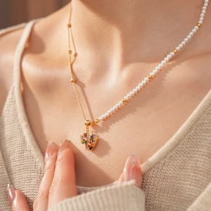 Detail of 18k gold plated necklace with heart zircon pendant and pearl beads on a model