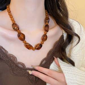 Close-up of irregular amber acrylic beads on a vintage necklace set for women