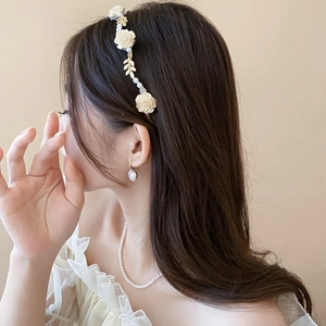 Détail du serre-tête floral avec roses blanches et perles porté par un modèle