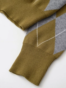 Macro shot of argyle knit fabric texture and ribbed cuffs on an olive green polo sweater
