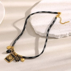 Macro view of rope chain necklace with 18K gold flower and cross square pendants
