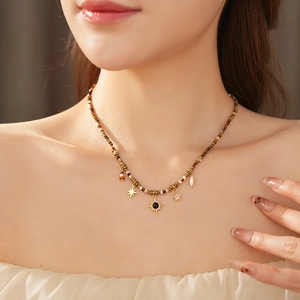 Detailed shot of ethnic beaded necklace featuring golden sun, star and shell charms