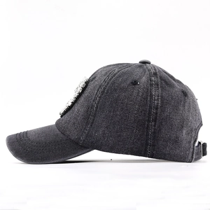 Side view of washed gray denim baseball cap with rhinestone shield patch and metal buckle