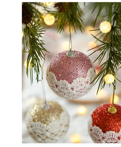 Close-up of 8cm glitter Christmas balls with white lace details on pine branches