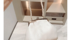 Nahaufnahme der weißen Abendtasche mit Perlengriff und Plisseestoff-Detail