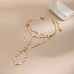 Close-up of golden multilayer chain bracelet with lobster clasp on minimalist stone