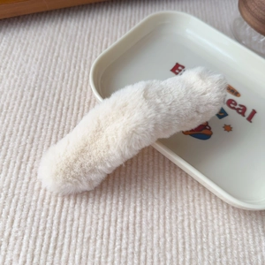 Detailed texture of creamy white plush hair clip made of soft artificial faux fur material