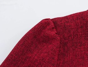 Dettaglio della trama del tessuto tweed rosso che mostra l'intreccio di un abito a maniche lunghe