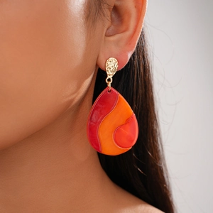 Close-up of teardrop resin earring with red-orange swirls and hammered gold stud