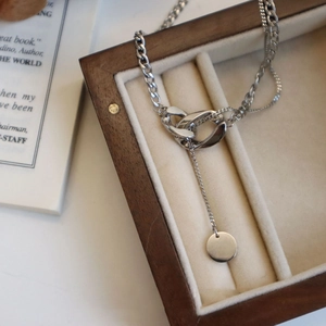 Détail des anneaux entrelacés et du pendentif rond sur un collier lariat argenté élégant