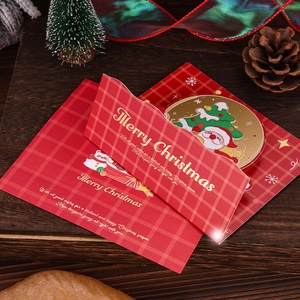 Close-up of a Christmas card with gold foil text on wood table with pine cones