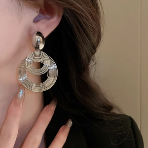 Close-up of model wearing silver multi-layer geometric circle earrings with metal texture