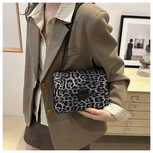 Detail of trendy leopard print shoulder bag with gold chain and black clasp on a blazer