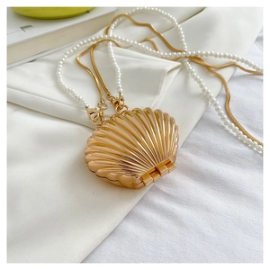 Close-up of shell-shaped golden crossbody bag with pearl strap and metallic chain