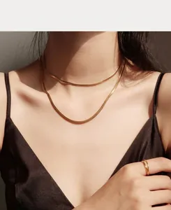 Detail of layered gold snake chain necklace and minimalist ring on a fashion model