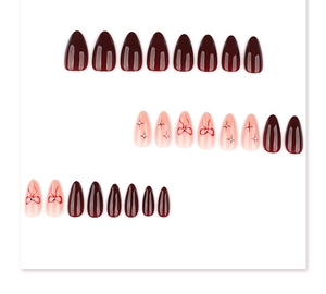 Detail of red almond press on nails featuring elegant bows and rhinestone starbursts