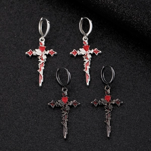 Close-up of Gothic cross earrings with red heart and rose details on black background