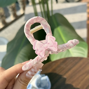 Pink and white checkered hair claw clip featuring a transparent bow in a close-up detail view