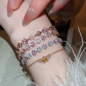 Detailed view of layered floral bracelets with pink crystals and pearls on wrist