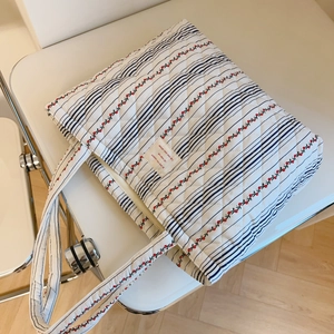 Vue détaillée du sac cabas matelassé aux motifs floraux et cerises sur une chaise