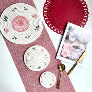 Three-piece set of round woven cotton coasters featuring pink peach and green leaf patterns