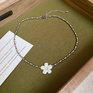Detailed macro view of a white flower pendant necklace with diamond on a green fabric base