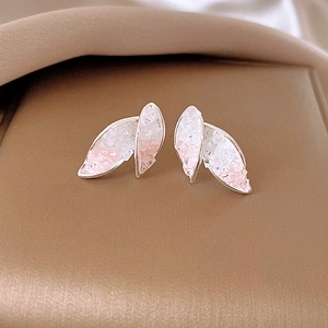 Detail of blue and pink glass bead butterfly earrings on beige fabric background