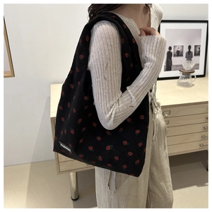 Close-up of black corduroy tote bag with red strawberry embroidery and fashion label